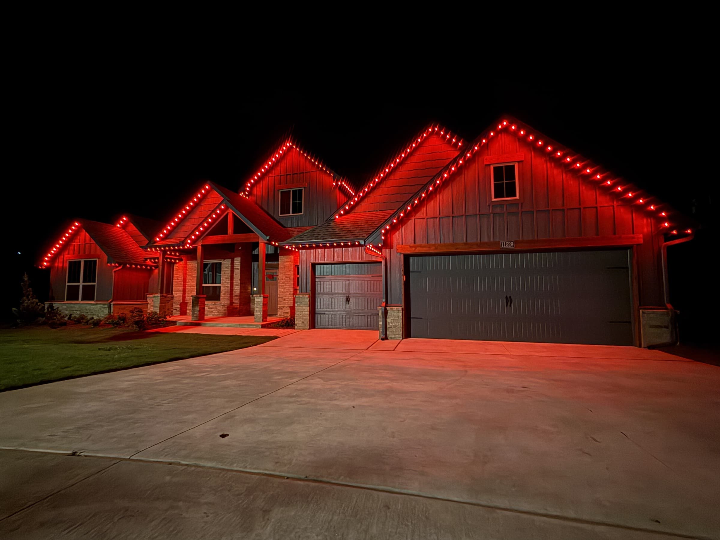 Multi-gable mixed-material home with TruLight permanent lighting set to a solid red roofline effect.