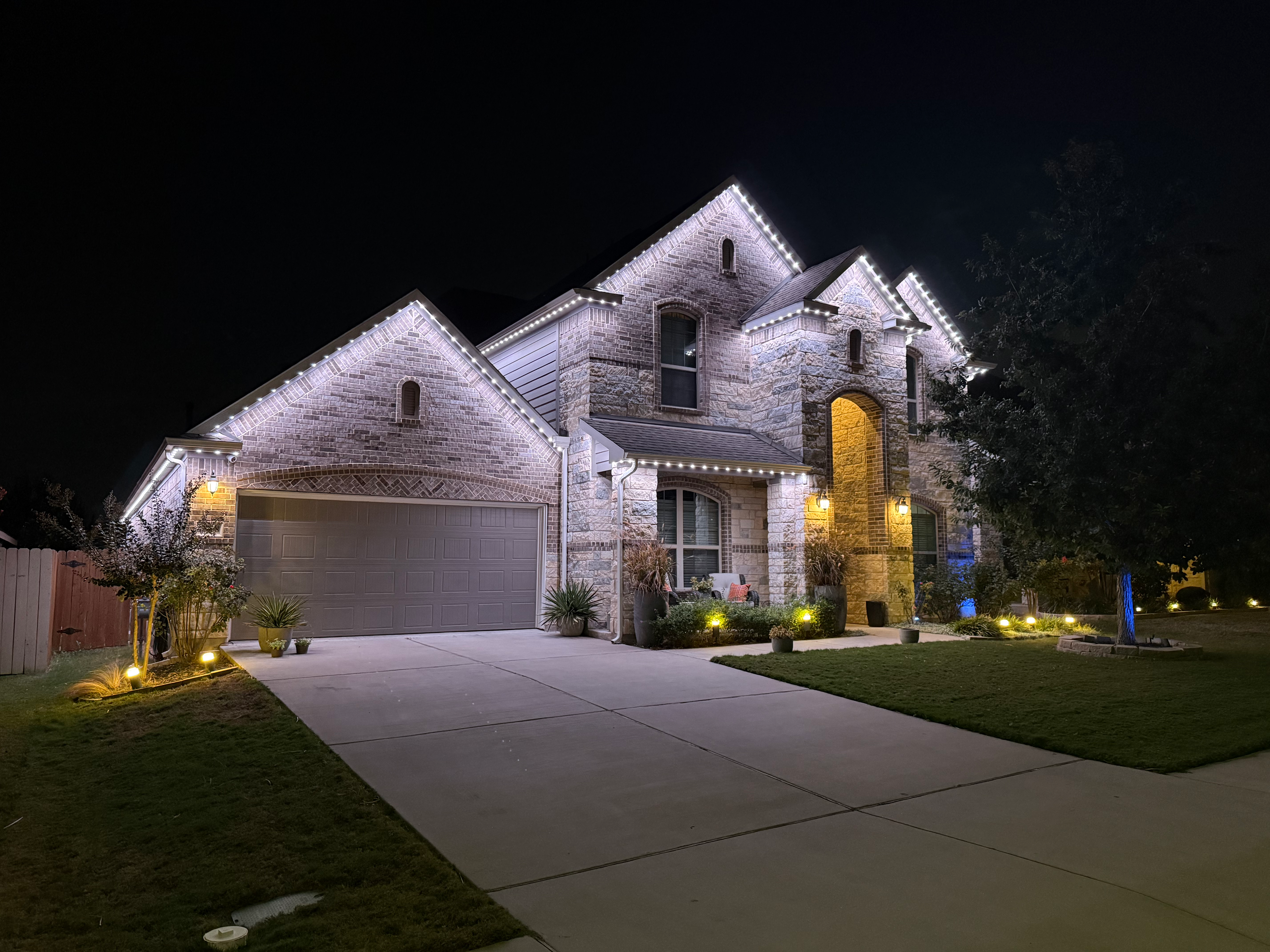 TruLight manufacturer example: Stone home with bright white LED roofline lighting at night