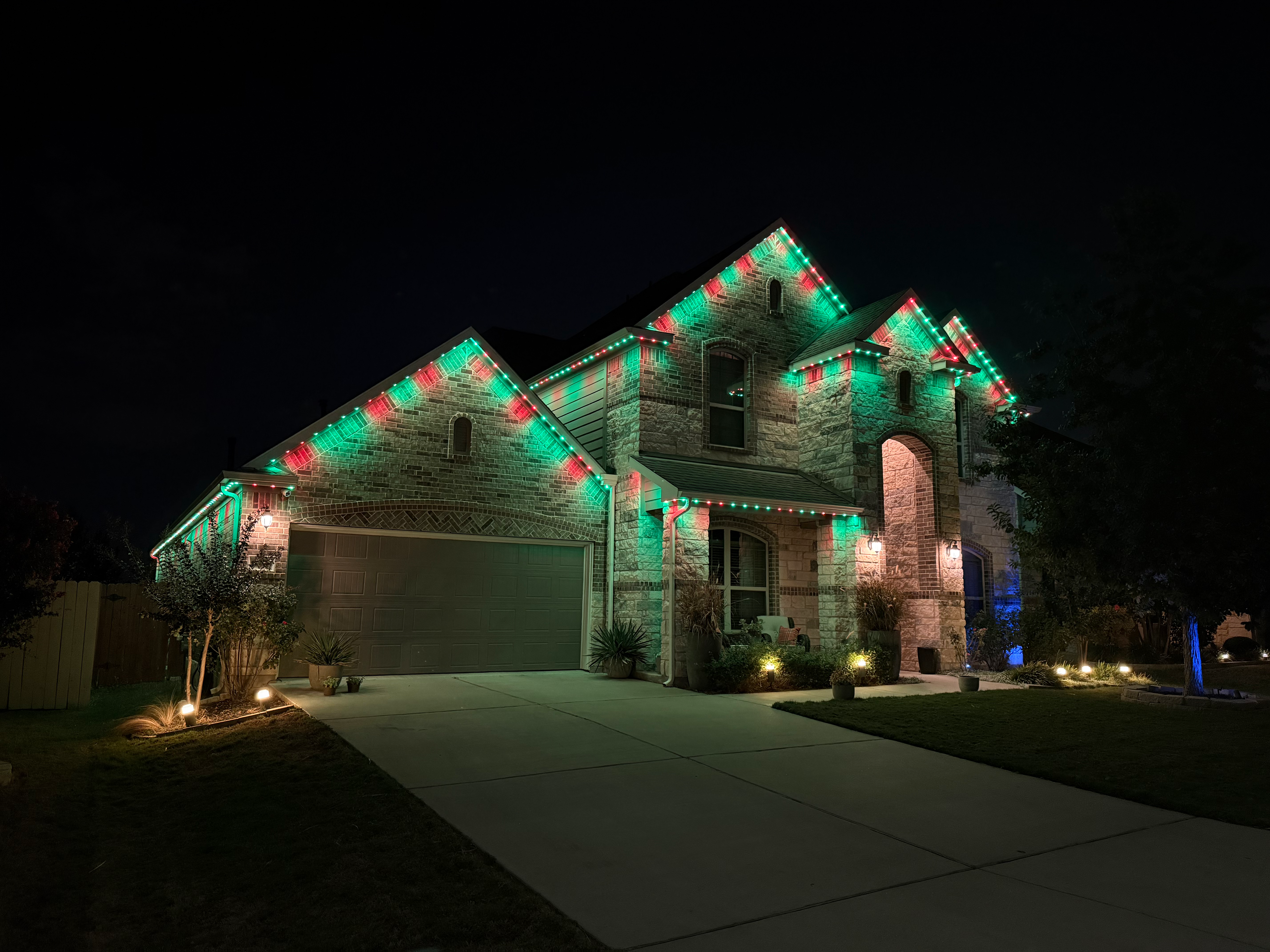 TruLight manufacturer example: Stone home with green, white, and red holiday LED lighting