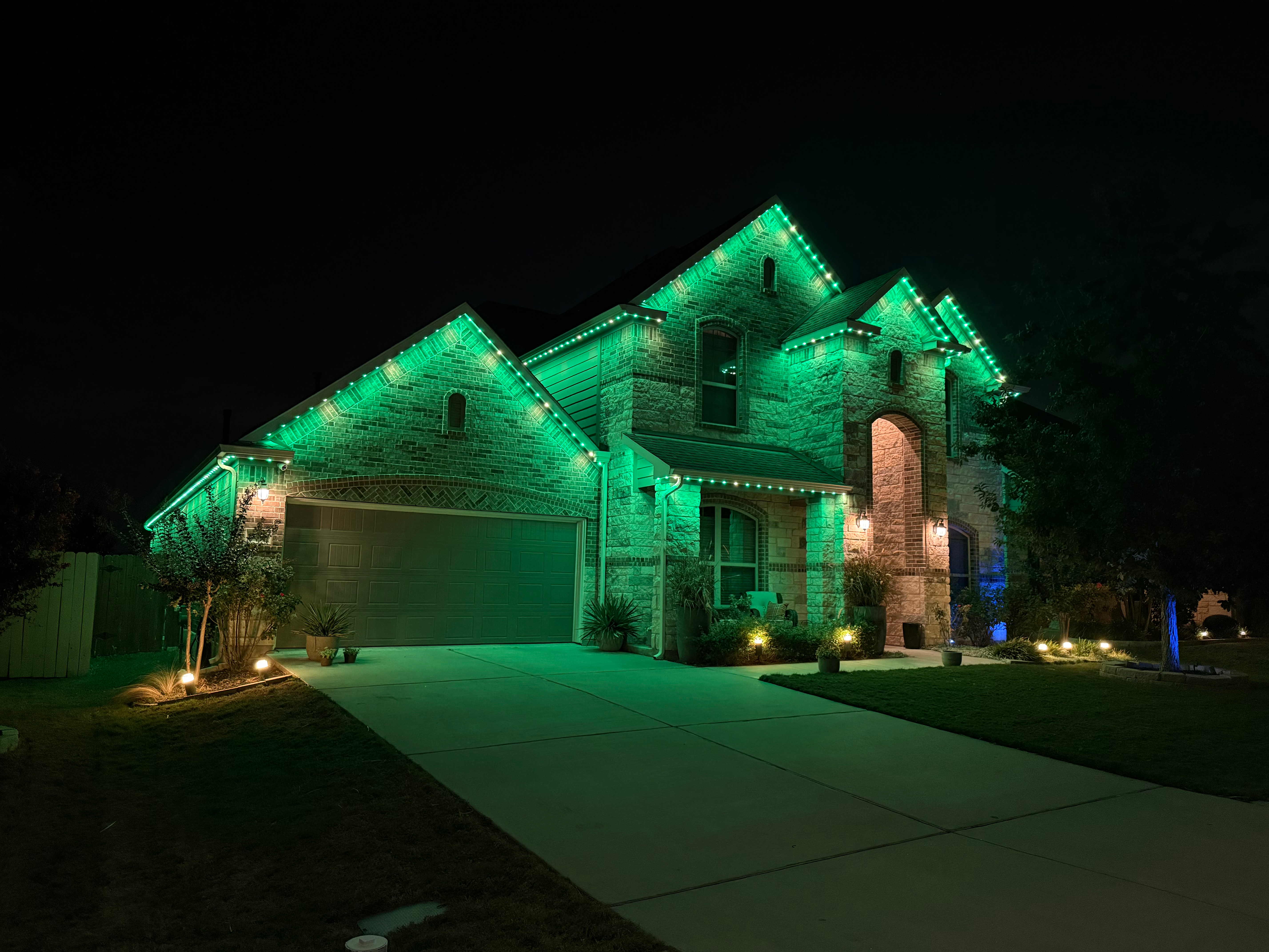 TruLight manufacturer example: Stone home with green and white LED roofline lighting