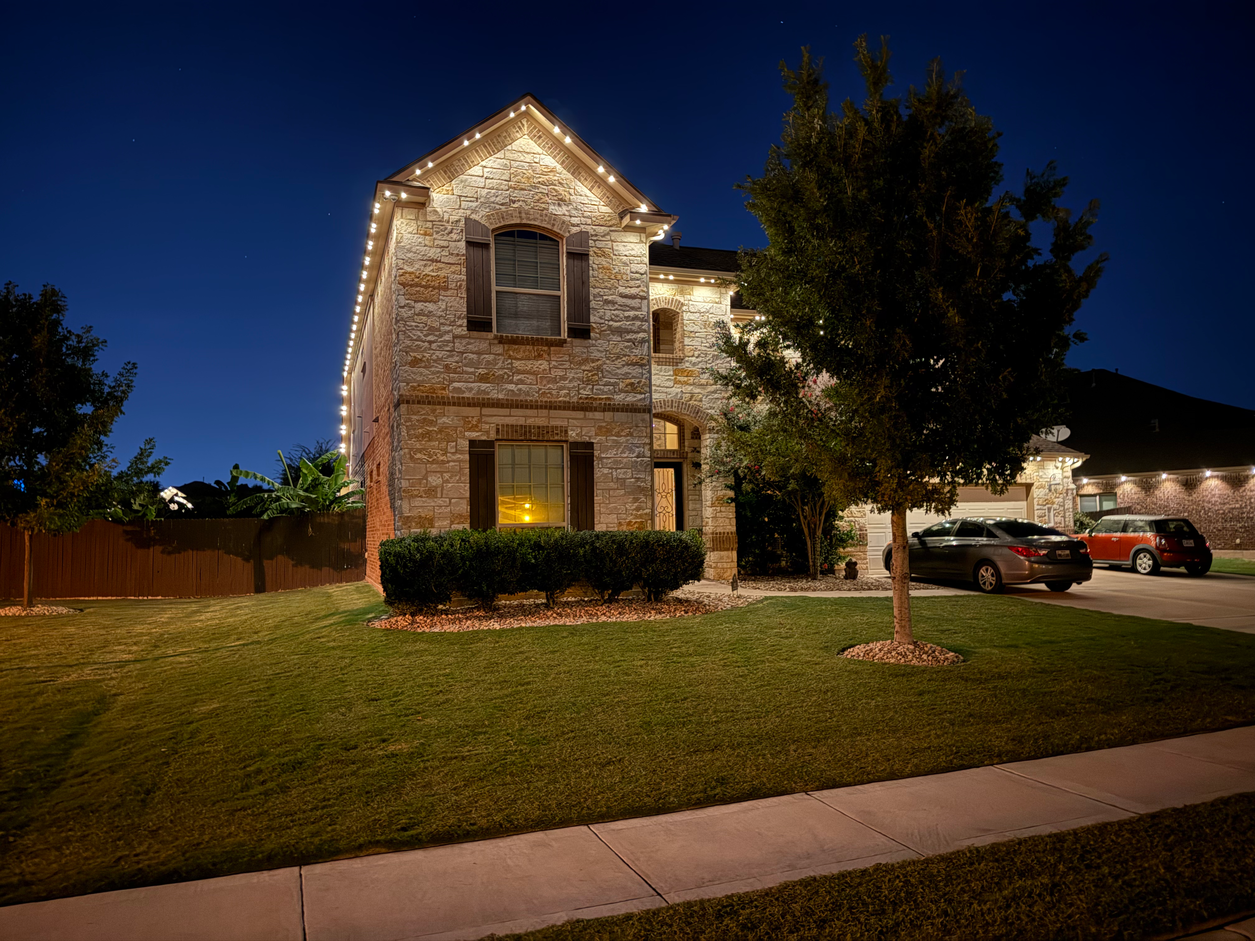 TruLight manufacturer example: Two story stone home with warm white LED roofline lighting